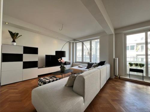 un soggiorno con divano bianco e TV di L'escapade Cathédrale - Plein centre avec balcon a Liegi