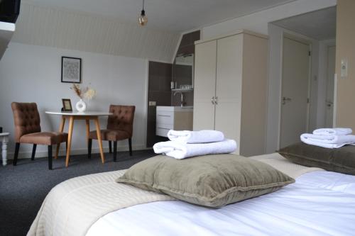 a bedroom with two beds and a table with chairs at Het Wapen van Noordwijkerhout in Noordwijkerhout