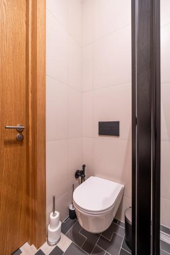 a white toilet in a bathroom with a door at Apartments with private parking & terrace in Jūrmala