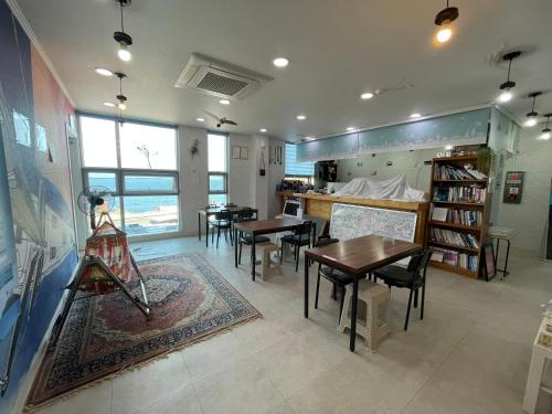 Yesjun Guest house في جيجو: غرفة معيشة مع طاولات وكراسي ومطبخ