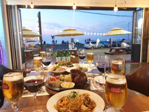 a table with plates of food and glasses of beer at Jeju Airport Hostel Yesjun in Jeju