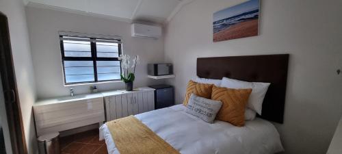 um pequeno quarto com uma cama e um lavatório em Three Little Birds Guesthouse em Durban