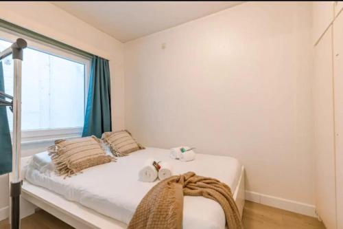 ein weißes Schlafzimmer mit einem Bett und einem Fenster in der Unterkunft ruim appartement aan zee in Ostende