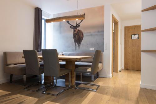 a dining room table with chairs and a deer painting on the wall at Aparthotel Herzblick GmbH in See
