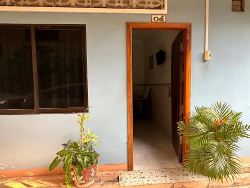 otwarte drzwi domu z roślinami obok niego w obiekcie Palm Tree Quest House w mieście Battambang