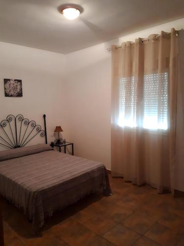 1 dormitorio con 1 cama y una ventana con cortinas en Chalet Piscina Privada Urbanización Roche Viejo, en Conil de la Frontera