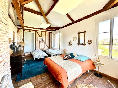 Un dormitorio con una cama naranja en una habitación con una pared de ladrillo en Authentique villa du XIX e siècle avec piscine, en Lue