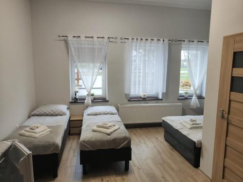 a bedroom with three beds and two windows at Pałac pod Bocianim Gniazdem in Runowo