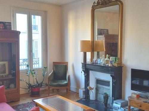 un salon avec une cheminée et un miroir dans l'établissement Large and cosy, Paris-Ouest, à Levallois-Perret