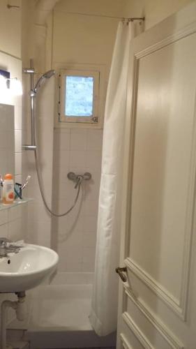 une salle de bain blanche avec une douche et un lavabo dans l'établissement Large and cosy, Paris-Ouest, à Levallois-Perret