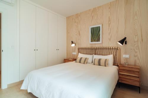 a bedroom with a large white bed with two pillows at Los Olivos Apartments by Olala Homes in Seville