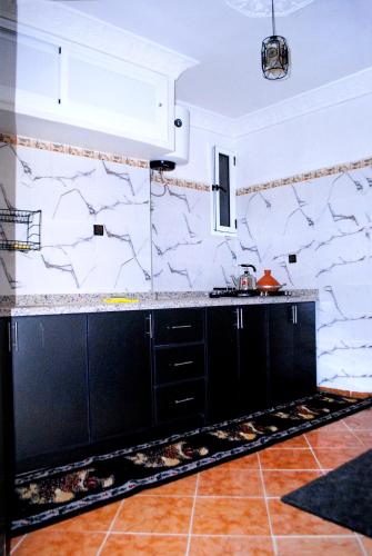 a kitchen with black cabinets and a stone wall at Airport apartment 1 