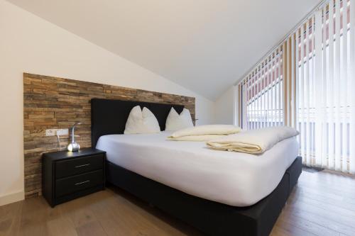 a bedroom with a large white bed with a brick wall at Aparthotel Herzblick GmbH in See
