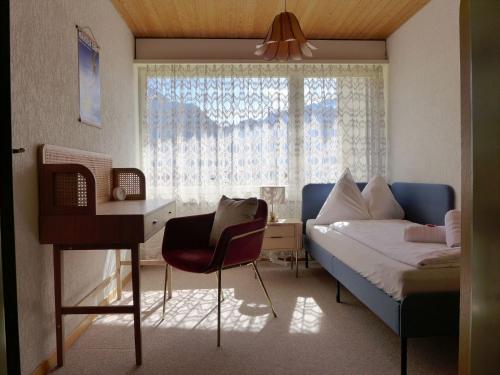 a bedroom with a bed and a desk and a window at Holiday Home Salzhubelweg by Interhome in Goldswil
