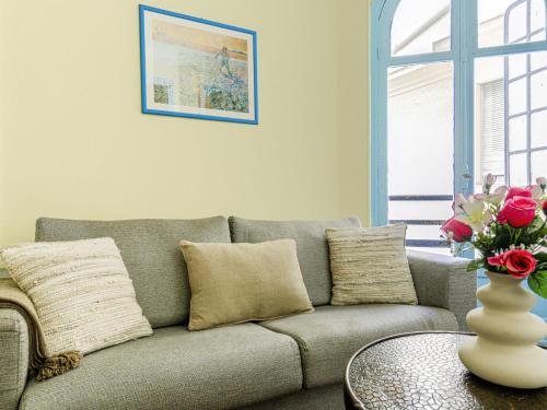 uma sala de estar com um sofá e um vaso com rosas em Apartment Les Colisées by Interhome em Nice