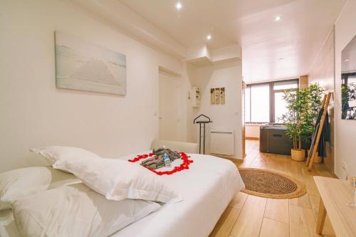 - une chambre avec un lit blanc orné de fleurs rouges dans l'établissement Spa appartement O temps suspendu Reims centre sauna et jacuzzi, à Reims