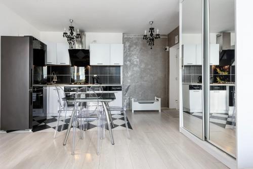 a kitchen with white cabinets and a table and chairs at Comfy Flat in the City Center in Warsaw