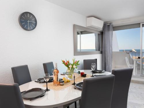 mesa de comedor con sillas y reloj en la pared en Apartment La Calypso-6 by Interhome, en La Grande-Motte