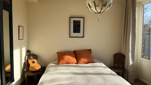 Un dormitorio con una cama con una guitarra. en appartement lumineux, en Montfort-lʼAmaury