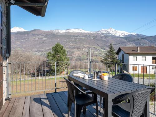 a wooden table and chairs on a deck with mountains at Apartment Maison Pro de Solari-2 by Interhome in Fenis