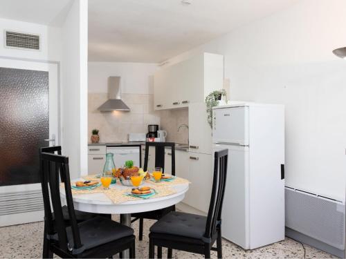a kitchen with a table and chairs and a white refrigerator at Apartment La Tour Fenestrelle by Interhome in La Grande Motte