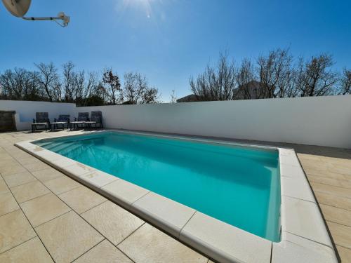 einen Pool auf einer Terrasse neben einer weißen Wand in der Unterkunft Holiday Home 4all by Interhome in Maslenica