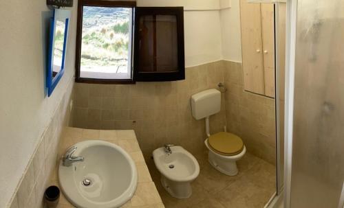 a bathroom with a sink and a toilet and a window at Dammusino: mini-appartamento in Pantelleria