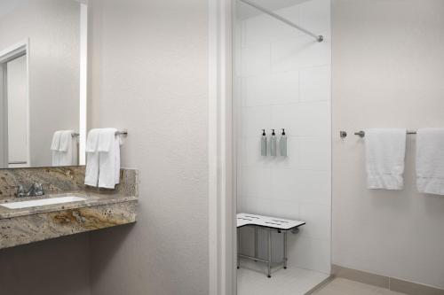 a white bathroom with a sink and a shower at Courtyard by Marriott Orlando East/UCF Area in Orlando