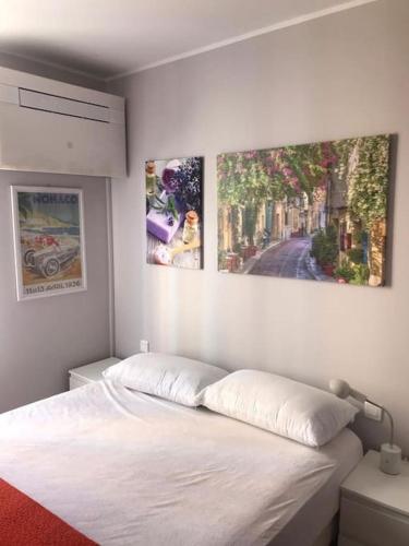 une chambre avec un lit avec deux tableaux au mur dans l'établissement Casa Charlotte nel cuore di Cannes, à Cannes