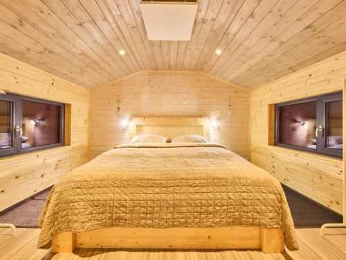 a bed in a wooden room with two windows at Chalet Lux chalet by Interhome in Mladé Buky