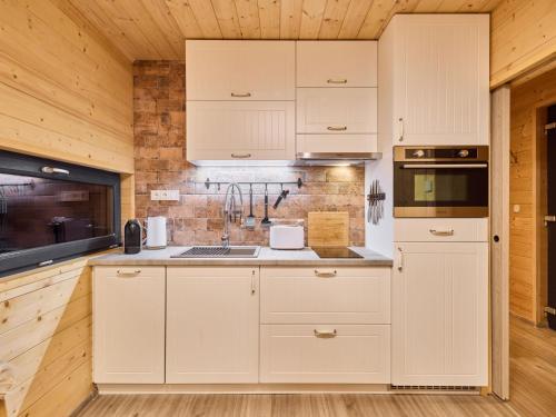 a kitchen with white cabinets and a brick wall at Chalet Luxe Timber Lodge & Yoga Loft by Interhome in Mladé Buky