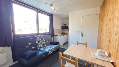 ein Wohnzimmer mit einem blauen Sofa und einem Tisch in der Unterkunft Le 3300 - 42 - Studio vue piste - 2 pers in Les Deux Alpes