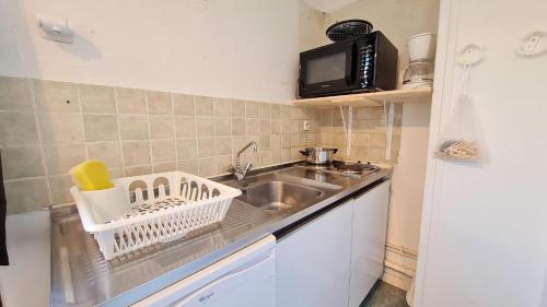 eine kleine Küche mit einer Spüle und einer Mikrowelle in der Unterkunft Le 3300 - 42 - Studio vue piste - 2 pers in Les Deux Alpes