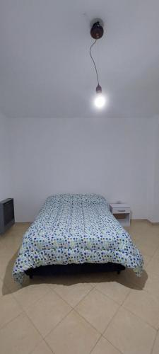 een bed in een witte kamer met een licht bij Los Maitenes 888 in Chos Malal