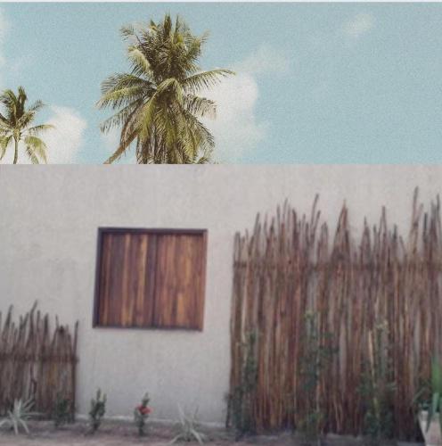 um edifício com uma janela e uma cerca com uma palmeira em Jeri laguna chalés paraiso em Jijoca de Jericoacoara