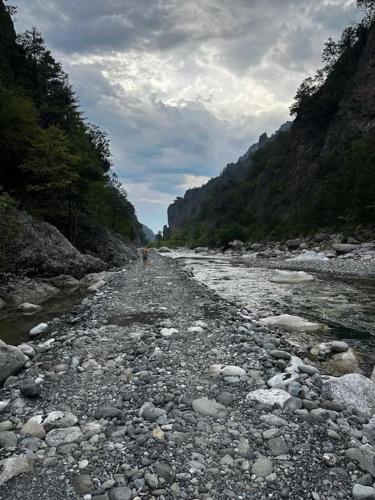 a rocky river with a person walking down the road at Casa Di Munti in Konitsa