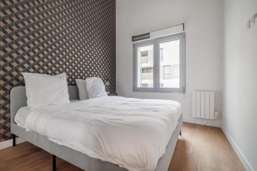 a bedroom with a bed with white sheets and a window at Chaleureux appartement6personnes in Asnières-sur-Seine