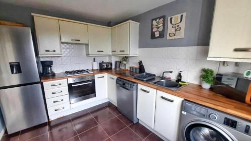 cocina con armarios blancos, lavadora y secadora en New - Modern Home from Home, 3 bedrooms, 2.5 bath en Plymouth