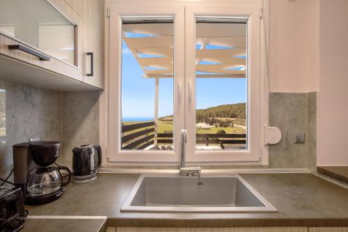uma cozinha com um lavatório e uma grande janela em Iliovasilema Holiday House em Volímai