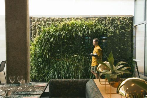 a man standing in front of a wall with plants at Salobre Hotel Resort & Serenity in Salobre