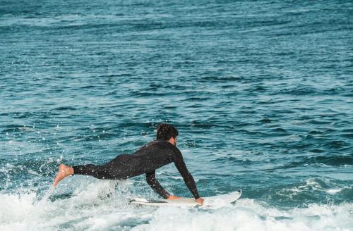un hombre montando una ola en una tabla de surf en el océano en Buendía Corralejo nohotel en Corralejo