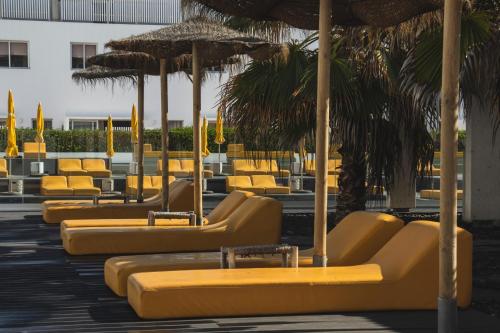 a row of yellow lounge chairs and umbrellas at Buendía Corralejo nohotel in Corralejo