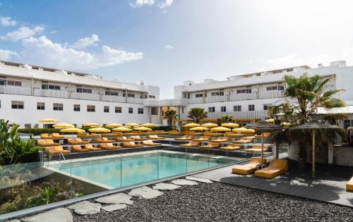 a hotel with a swimming pool and lounge chairs at Buendía Corralejo Nohotel in Corralejo