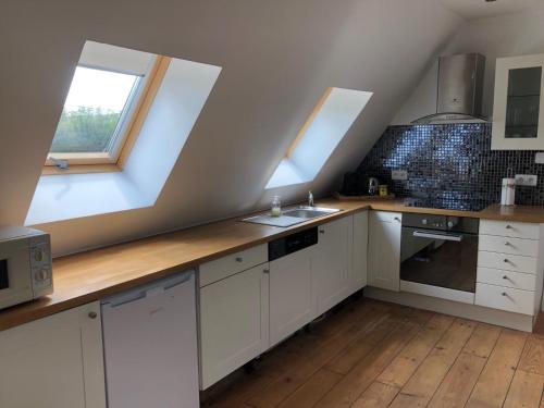- une cuisine avec des placards blancs et 2 lucarnes dans l'établissement Gîte chez Annelies, au Bugue