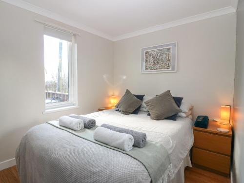 a bedroom with a white bed with towels on it at Caldwell Cottage in Lanark