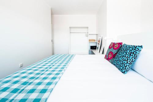 a white bedroom with a bed with a blue and white checkered blanket at Buendía Corralejo Nohotel in Corralejo