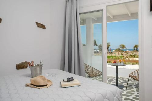 a white bedroom with a bed with a hat and books at Glaronissi Beach in Plaka
