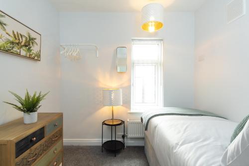 a bedroom with a bed and a lamp and a window at Heath House in Burton upon Trent