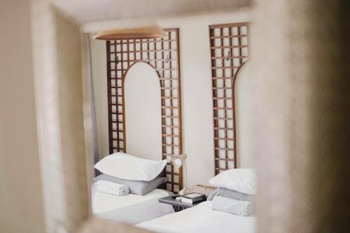 um espelho reflexo de um quarto com almofadas brancas e uma cama em Kate's Nest Guesthouse em Windhoek