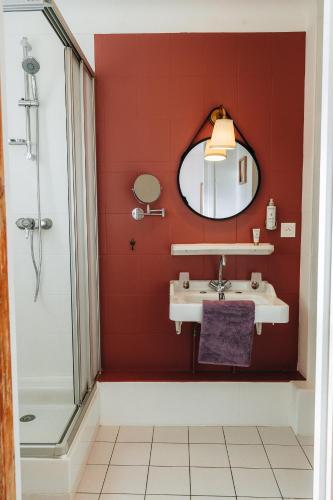 a red bathroom with a sink and a mirror at Hôtel l'Abbaye in Saint-Cyprien